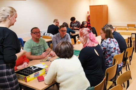 na zdjęciu osoby siedzące przy stolikach, grające w gry planszowe. Kliknij, aby powiększyć zdjęcie.